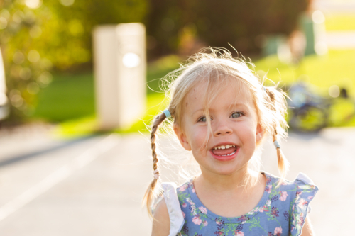 Happy young Australian girl with messy hair outside home in sunlight - Australian Stock Image