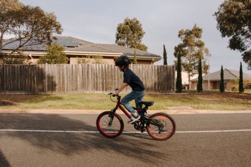 Happy young boy riding his bicycle on the street. - Australian Stock Image