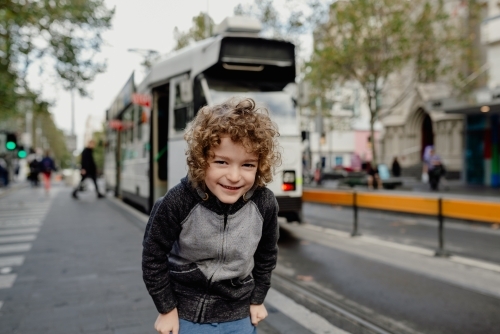 Happy young boy standing at a tram station in Melbourne City CBD - Australian Stock Image