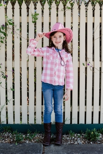 Happy young girl dressed up as a cowgirl wearing a pink akubra hat and pink and white shirt - Australian Stock Image