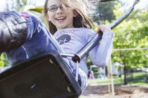 Happy young girl swinging on swing