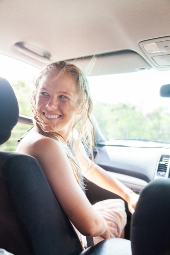 Happy young woman in passenger seat of car coming home from a beach day with friends - Australian Stock Image