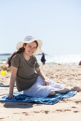 Happy young woman in sunhat on bright beach - Australian Stock Image