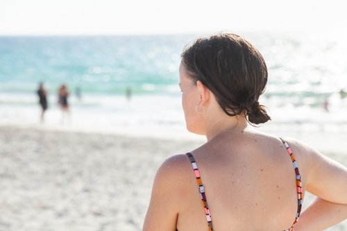Happy young woman on sunlit beach in summer wearing swimmers - Australian Stock Image