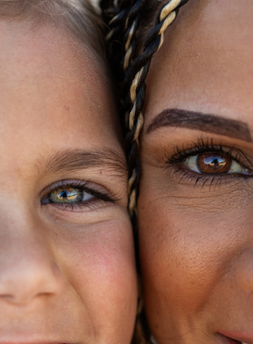 Hazel and brown eyes of First Nations Australian girl and mother with faces close together - Australian Stock Image