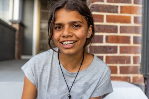 head and shoulders of happy girl with a wide smile sitting outside home - Australian Stock Image