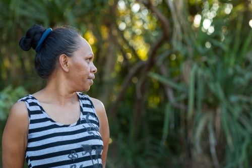 head and shoulders of mature woman in profile wearing striped singlet outdoors - Australian Stock Image