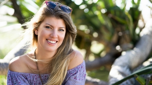 Headshot of pretty woman with blonde hair sitting outdoors - Australian Stock Image