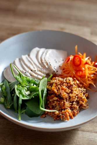 Healthy chicken and salad dish on wooden table in cafe - Australian Stock Image