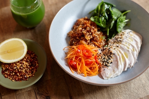 Healthy chicken and salad dish on wooden table in cafe - Australian Stock Image