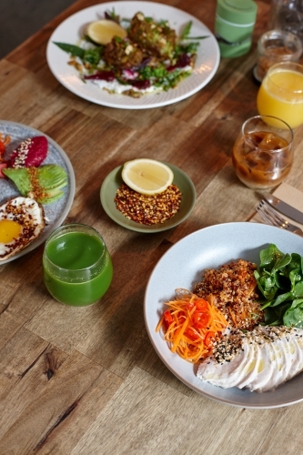 Healthy chicken and salad dish on wooden table in cafe - Australian Stock Image