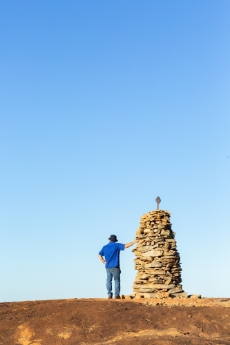 Hiker atop granite outcrop next to rock cairn - Australian Stock Image