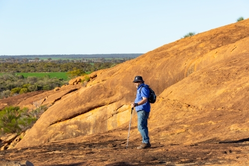 hiker standing on granite rock in the wheatbelt - Australian Stock Image