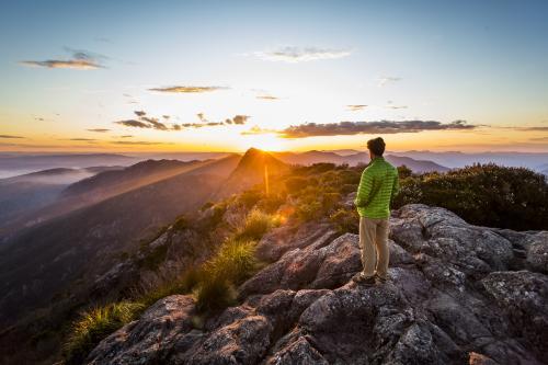 Hiker watching mountain sunset from the east peak of Mount Barney - Australian Stock Image