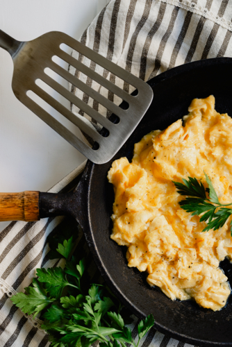 Home cooked scrambled eggs for breakfast served in a skillet frying pan garnished with parsley - Australian Stock Image