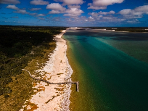 horizontal shot of a beach walkway with bushes, trees and waves on a sunny day - Australian Stock Image