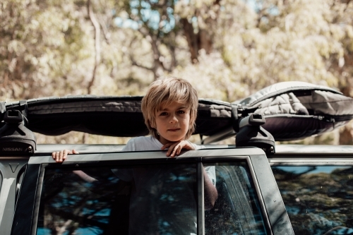 Horizontal shot of a boy leaning on the car door - Australian Stock Image