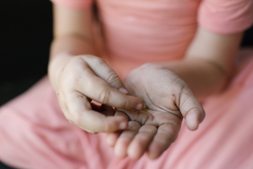 Horizontal shot of a child's hand holding small pieces of objects. - Australian Stock Image