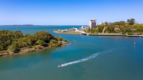 Horizontal shot of a jetski heading to the left away from industry - Australian Stock Image