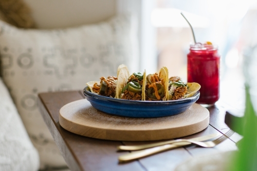 Horizontal shot of a plate of tacos and red juice on a wooden table - Australian Stock Image