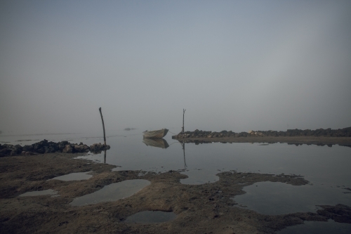 Horizontal shot of a row boat on an inlet in a misty morning - Australian Stock Image