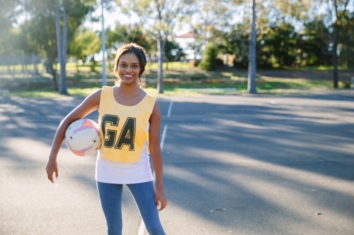 horizontal shot of a young smiling woman holding a net ball - Australian Stock Image