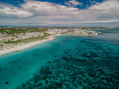 horizontal shot of beach with white sand shoreline, trees, bushes and buildings on a sunny day - Australian Stock Image