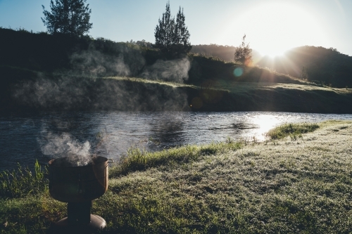 horizontal shot of river at sunset with trees, grass, and mountains - Australian Stock Image