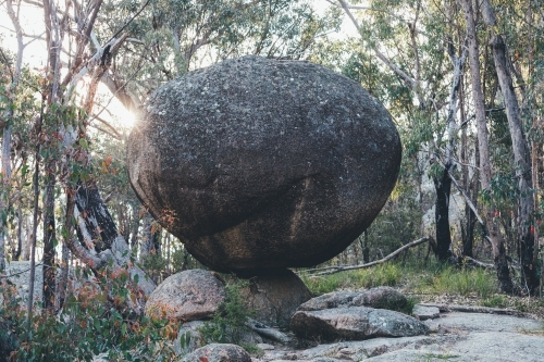 horizontal shot of rocks stacked on top of each other with trees at the back on a sunny day - Australian Stock Image