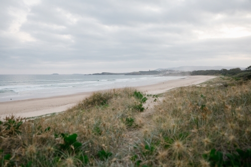 Horizontal shot of shoreline with beach waves at sunset - Australian Stock Image