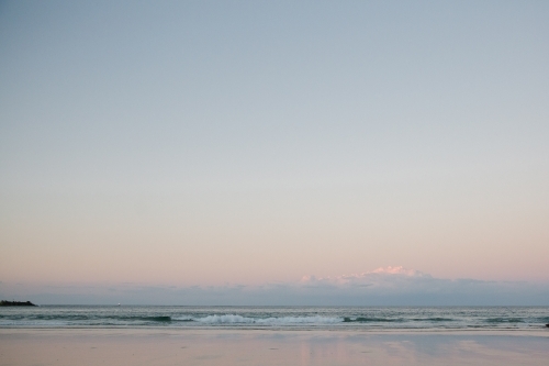 Horizontal shot of shoreline with beach waves at sunset - Australian Stock Image