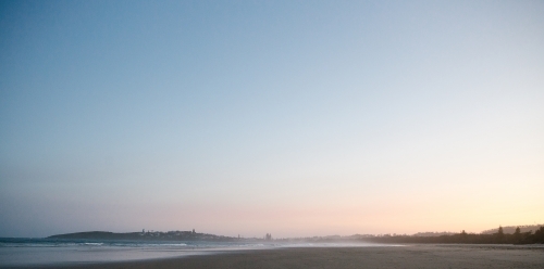 Horizontal shot of shoreline with beach waves at sunset - Australian Stock Image