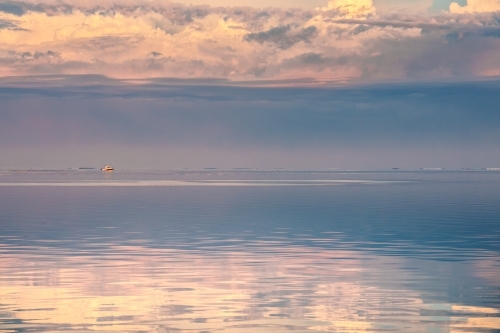 Horizontal shot of sunset clouds reflecting in the ocean - Australian Stock Image