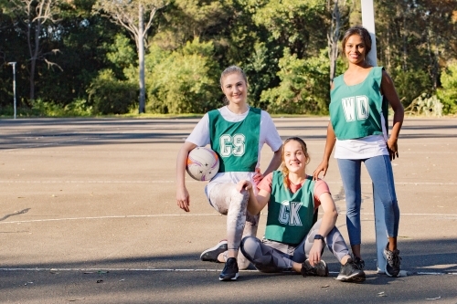 horizontal shot of three young smiling women in sports wear posing for a photo op on a sunny day - Australian Stock Image