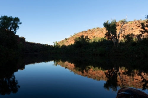 Horizontal shot of trees and mountains reflecting shadows in the water. - Australian Stock Image