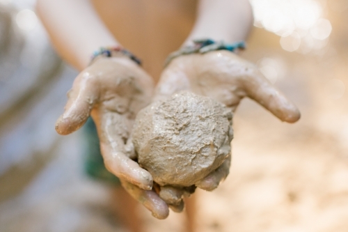 Horizontal shot of two hands holding a molded ball of clay - Australian Stock Image