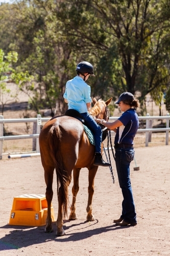 Horse riding instructor giving lesson to student on horseback - Australian Stock Image