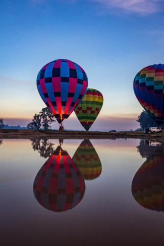 Hot air balloons taking off and reflected over lake at sunrise - Australian Stock Image