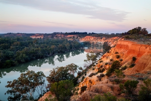 houseboat moored near bend in river at sunset - Australian Stock Image