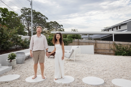 Husband and wife holding hands in backyard - Australian Stock Image