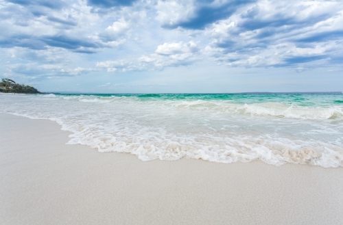 Hyams Beach waves wash ashore onto pristine white sands - Australian Stock Image