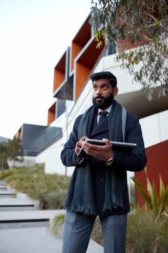 Indian architect using touchscreen device to survey site - Australian Stock Image