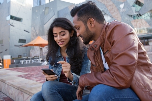 Indian Couple looking at a phone in Federation Square - Australian Stock Image