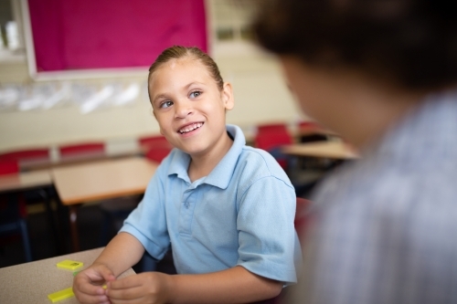 Indigenous girl student talking to a friend in a classroom - Australian Stock Image