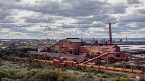 Industrial landscape of steelworks pelletising plant & train delivering iron ore from the mine - Australian Stock Image