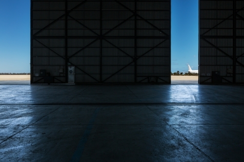Inside an airport hangar looking out to the runway - Australian Stock Image