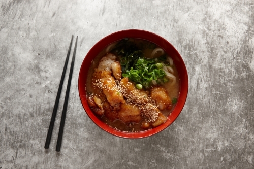 Japanese chicken noodle soup in red bowl - Australian Stock Image