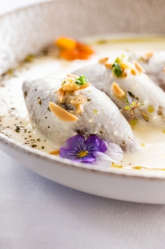 Kibbeh in creamy white sauce garnished with nuts and fresh herbs. - Australian Stock Image