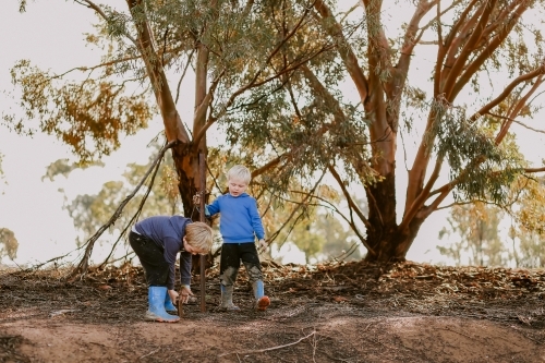 Kids exploring the bush in winter wearing blue gumboots - Australian Stock Image