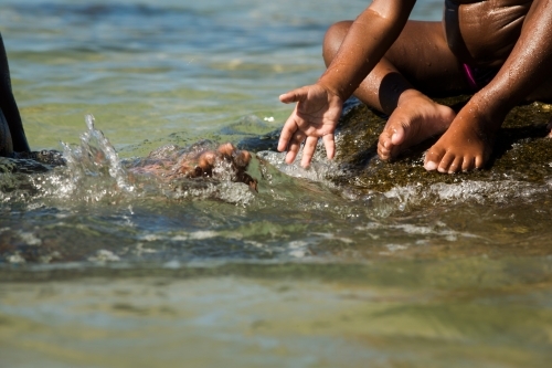 Kids playing in the shallow waters of the ocean. - Australian Stock Image